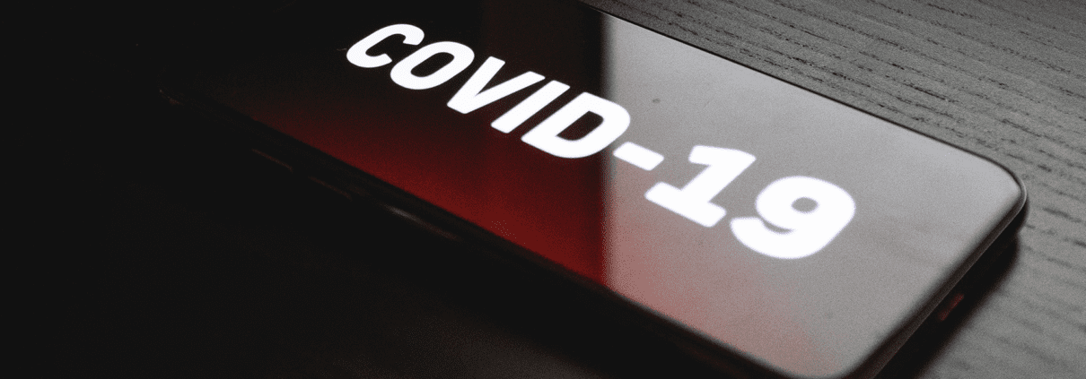 COVID-19 embossed and painted white on a red plastic see-through button.