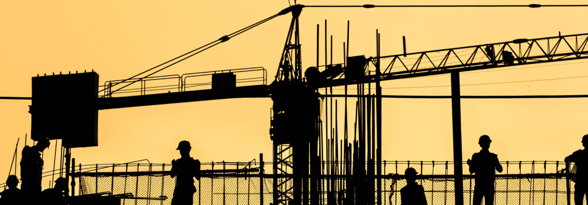 silhouettes of construction workers at the end of day