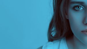 Styalised image of woman looking toward the camera with a blue filter over top.